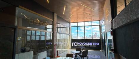 Decoração moderna com divisórias de vidro, vista para a cidade e uma placa para Novocentro.