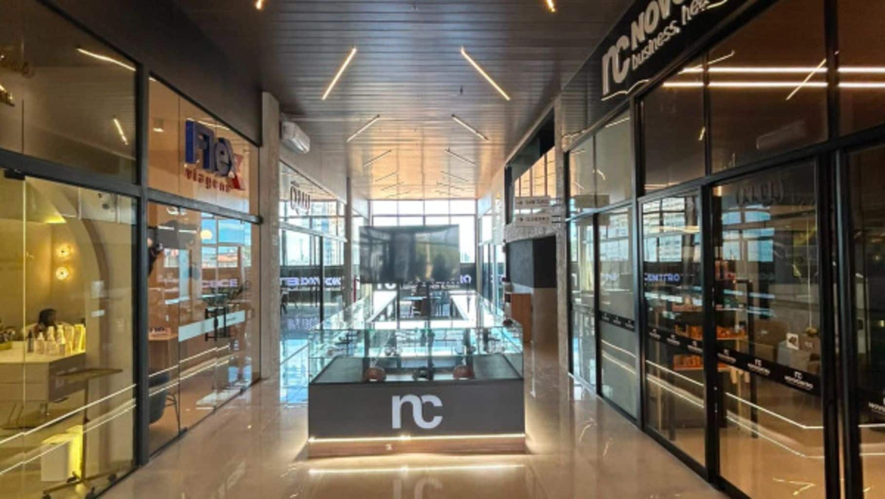 A modern indoor shopping area with glass display cases and a central 'nc' sign.
