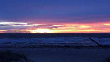 A beach scene with a sunset over the ocean.