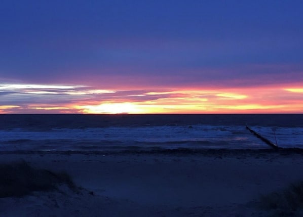 Une scène de plage avec un coucher de soleil sur l’océan.