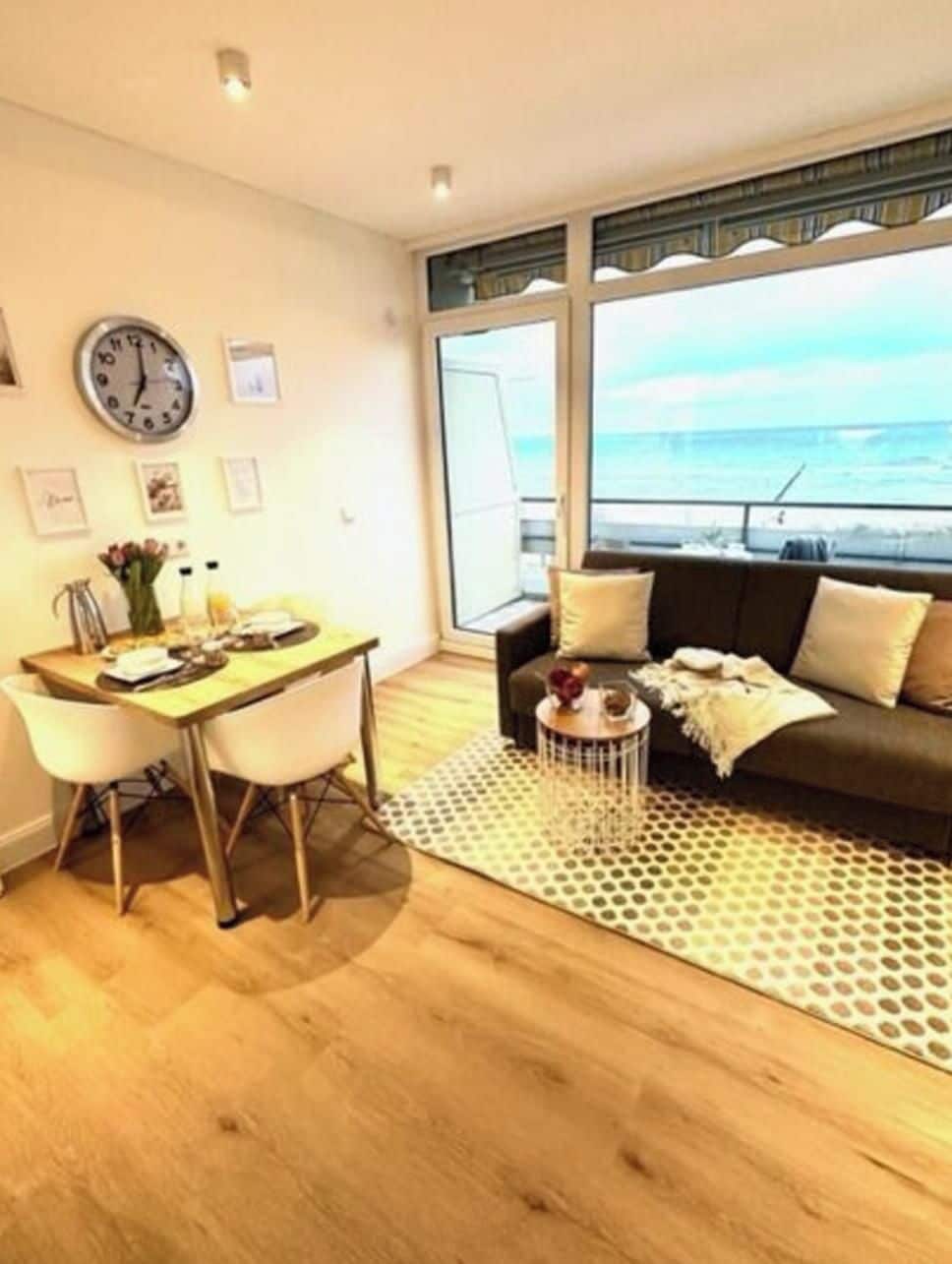 A living room with a dining area, a sofa, a coffee table, and a view of the sea.