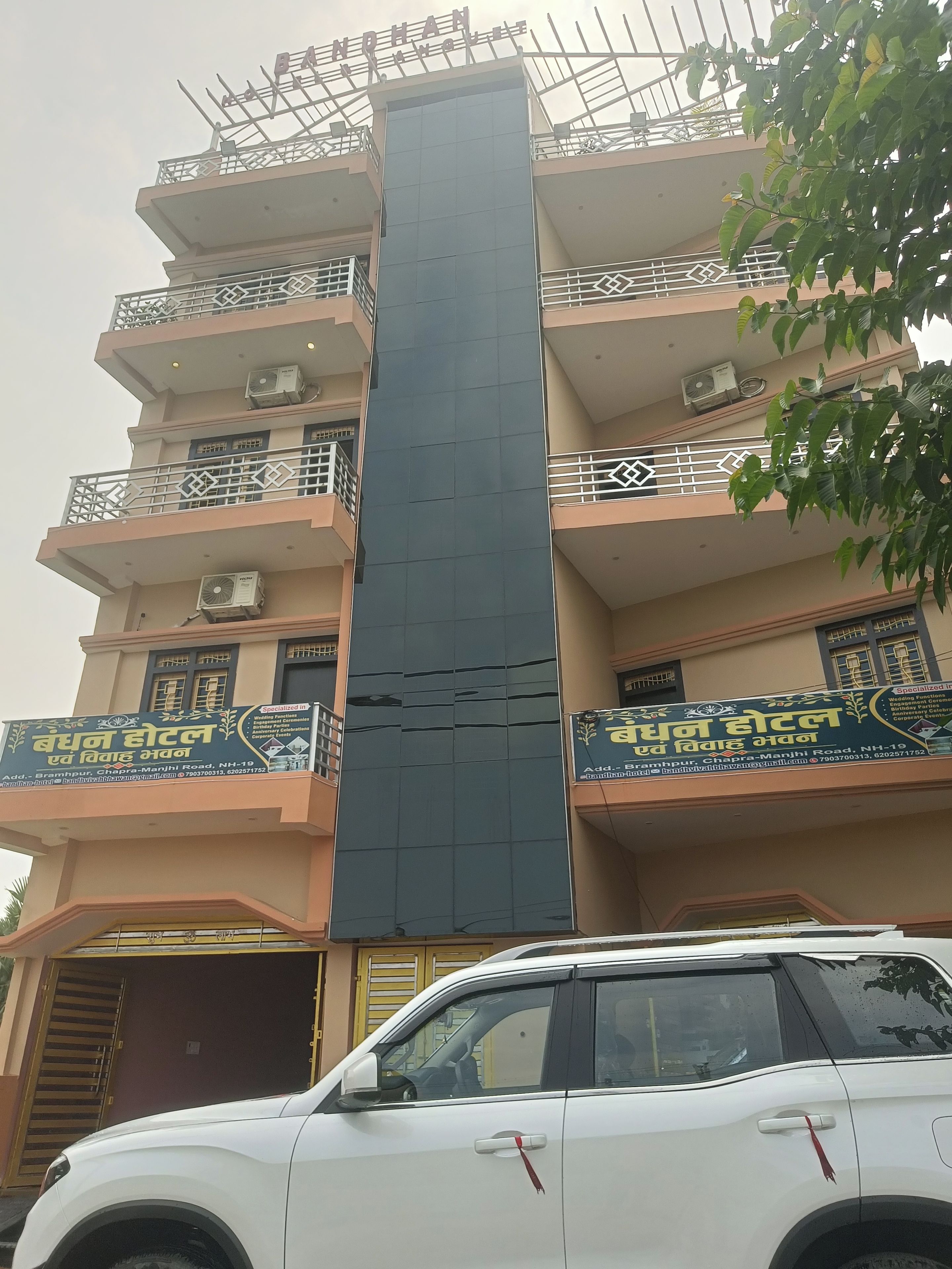 A multi-story hotel with balconies, air conditioning units, and a large central pillar.