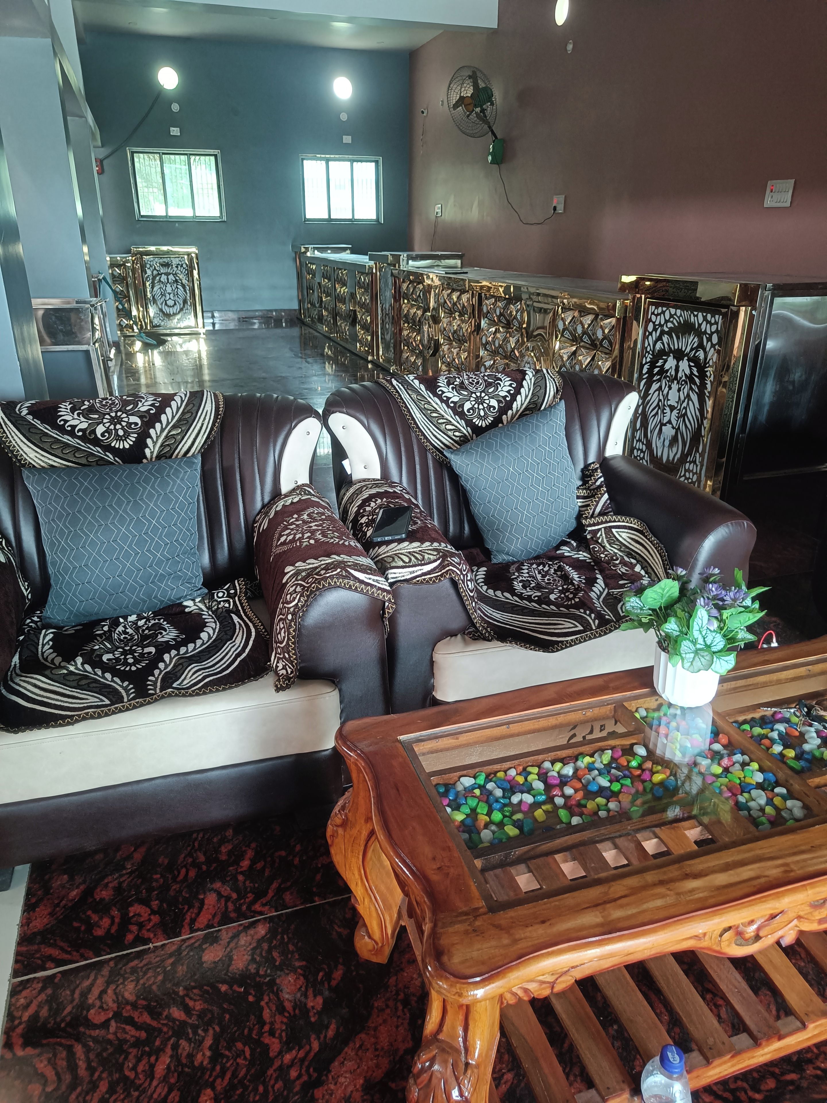 A spacious living area with a leather sofa, a wooden coffee table with colorful pebbles, and a decorative lion head on the wall.