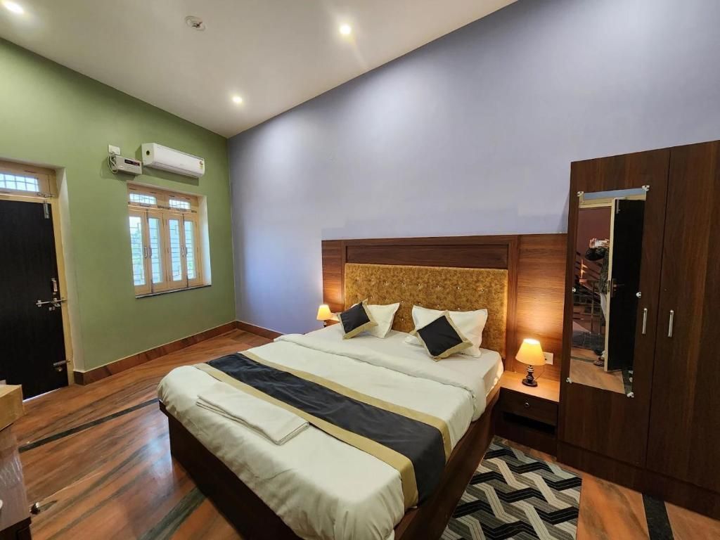 A hotel room with a large bed, wooden headboard, two bedside lamps, a wardrobe, and a window with a view.