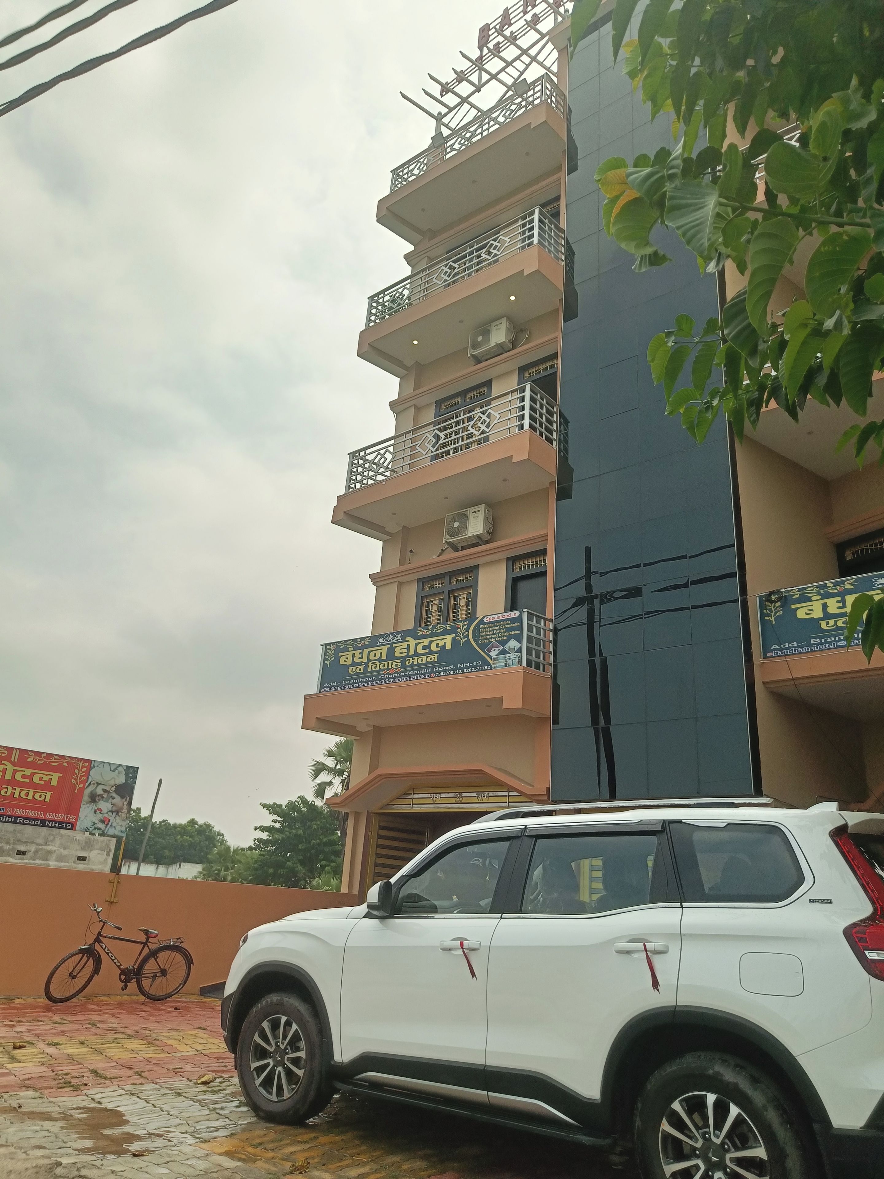 A multi-story building with balconies, a parked white SUV, and a bicycle.