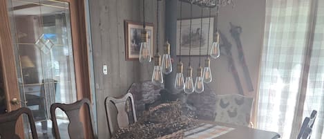 Een eetgedeelte met een lange houten tafel, stoelen, een geweven middelpunt en hanglampen.