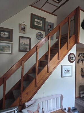 A wooden staircase with a handrail, leading to a landing with a white railing.