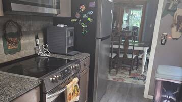 A kitchen with a microwave, stove, refrigerator, and a rug.