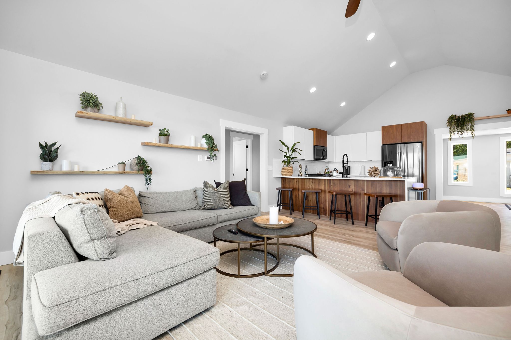 A modern living room with a sectional sofa, a round coffee table, and a kitchen area with a bar.