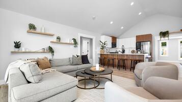 A modern living room with a sectional sofa, a round coffee table, and a kitchen area with a bar.
