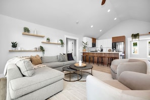 A modern living room with a sectional sofa, a round coffee table, and a kitchen area with a bar.
