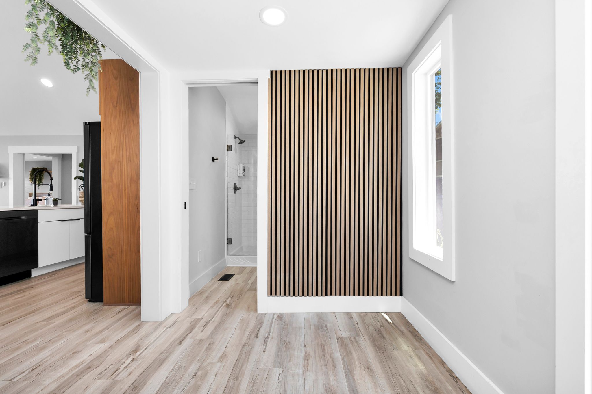 Un interior moderno con cocina, zona de ducha y pared decorativa de madera.