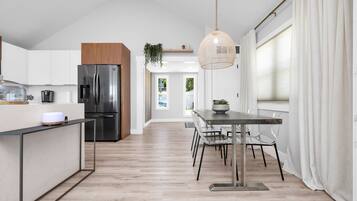 Una cocina moderna con refrigerador integrado, armarios de madera y un comedor con mesa y sillas.
