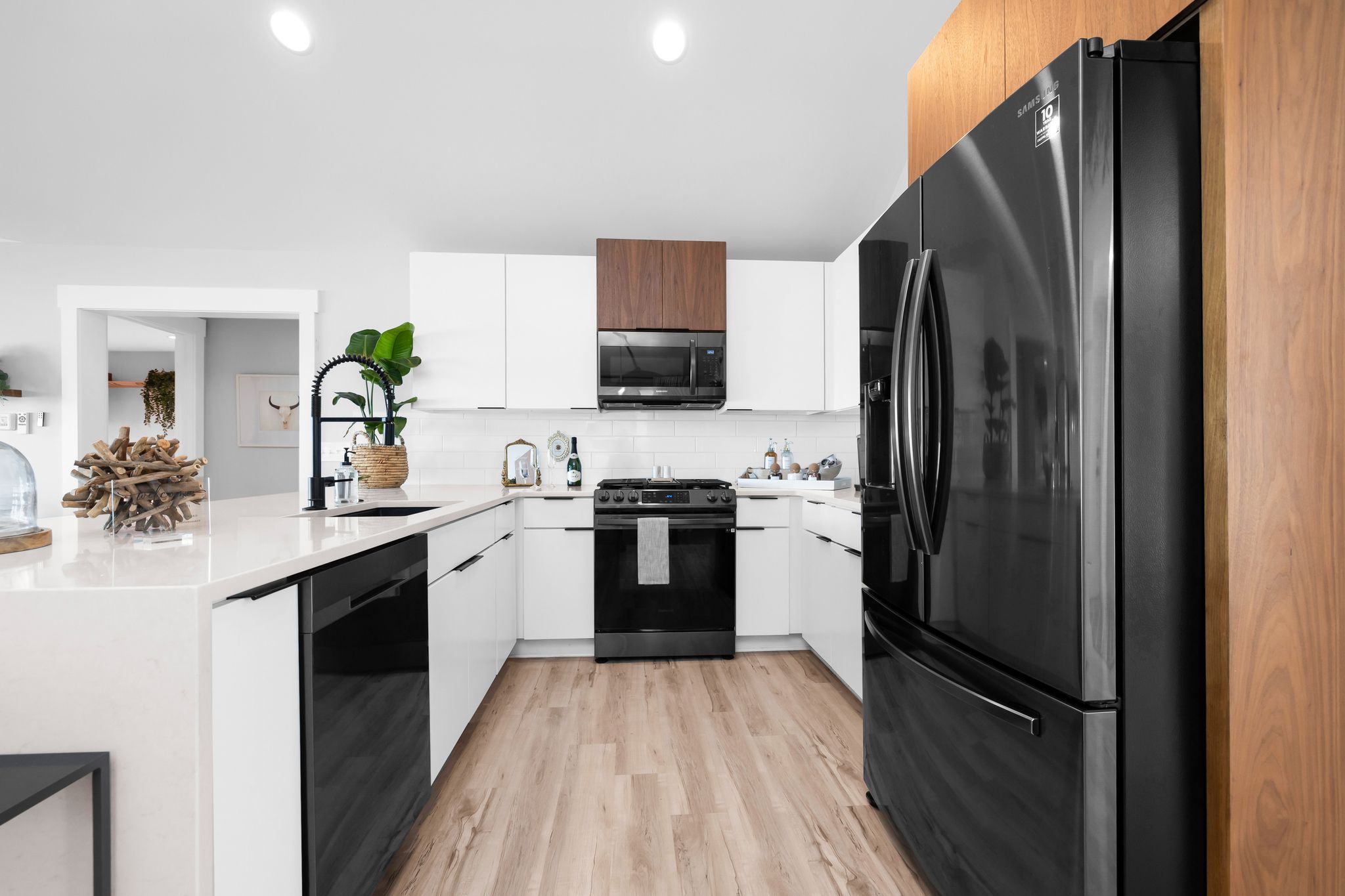 Una cocina moderna con armarios blancos, un refrigerador negro y una estufa de acero inoxidable.