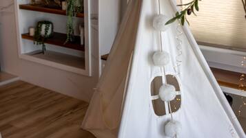 A white tent with a rope entrance, decorative pom-poms, and a string of lights.