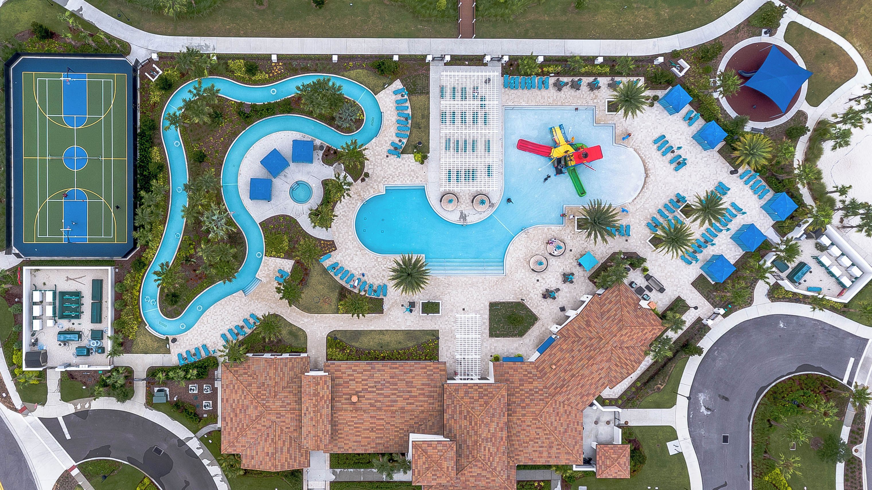 An aerial view of a resort with a swimming pool, a tennis court, and a covered seating area.