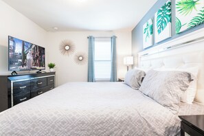 A bedroom with a large bed, a TV on a dresser, a window with curtains, and wall art. - Special Offer- 1min walk to Clubhouse, with SPA, Luxury 7BD Home 8900 (Kissimmee)
