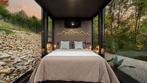 Ein modernes Schlafzimmer mit einem Bett, Kissen und einem Wandbild mit Bergmotiven.