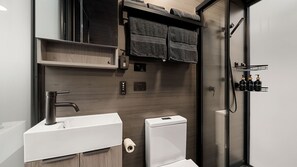 Une salle de bain moderne avec un lavabo blanc, des toilettes et une douche à parois de verre.