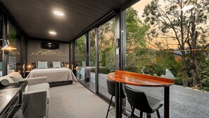 Une chambre moderne avec un grand lit, un bureau et une vue sur les arbres et les montagnes.