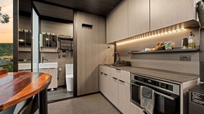 Une cuisine moderne dotée d’un plan de travail en bois, d’appareils électroménagers en acier inoxydable et offrant une vue sur l’extérieur.