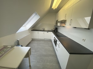 A compact kitchen with white cabinets, a black countertop, and a skylight. - Regina House 11 (Timmendorfer Strand)