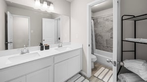 A modern bathroom with a double sink vanity, a large mirror, and a shower area. - Comfort Meets Space - Feel Right at Home (Cypress)