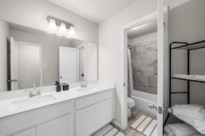 Une salle de bain moderne avec un meuble-lavabo à deux vasques, un grand miroir et un espace douche.