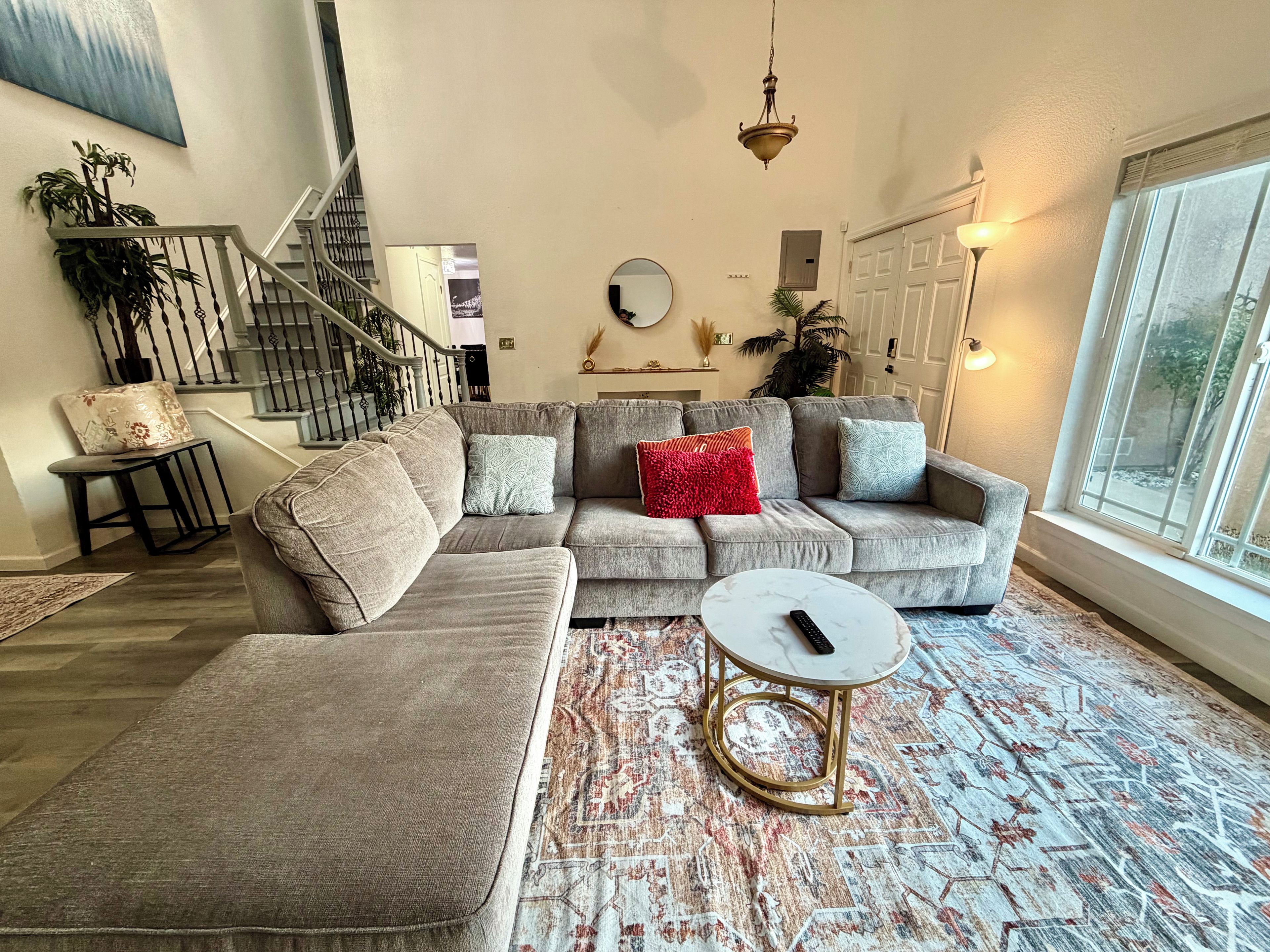 A modern living room with a sectional sofa, a round coffee table, and a staircase.