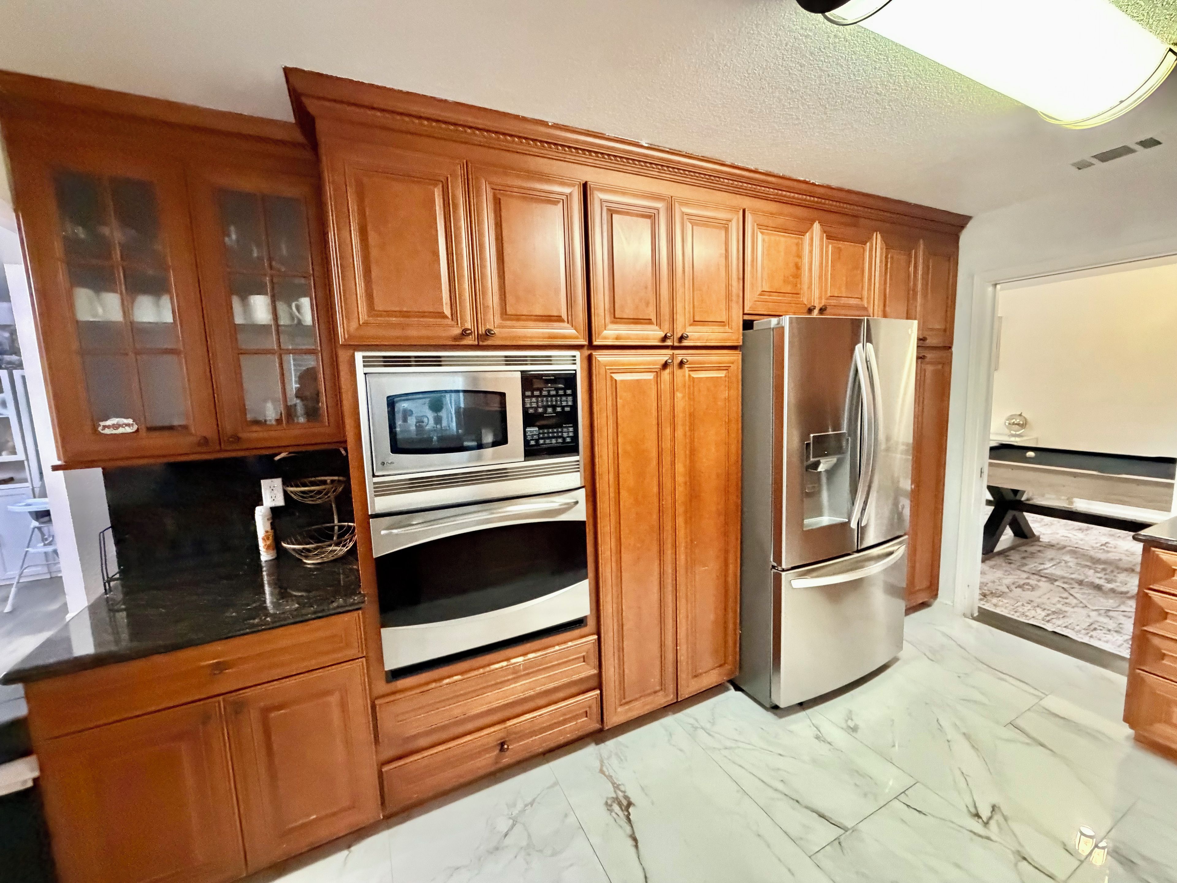 A kitchen with wooden cabinets, a stainless steel refrigerator, and a microwave.