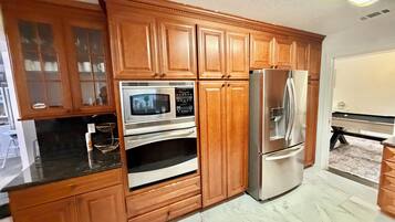 A kitchen with wooden cabinets, a stainless steel refrigerator, and a microwave.