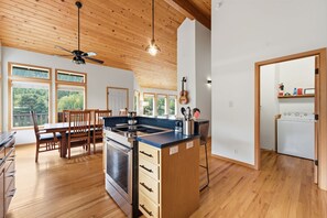 Eine moderne Küche mit Holzboden, einer zentralen Kochinsel und einem Essbereich mit Holzstühlen.