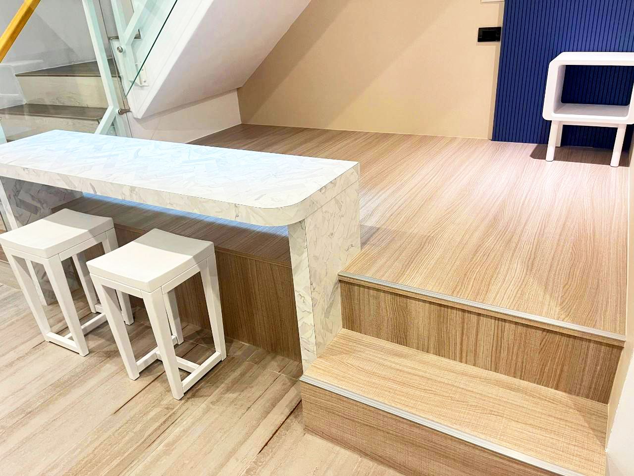 A bar area with a marble countertop and two white stools.