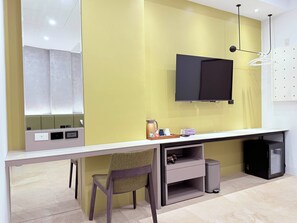 A modern room with a long desk, a chair, a mounted TV, and a wall-mounted shelf with a kettle and cups. - Xingwan (Kaohsiung)