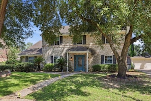 A two-story house with a stone facade, a blue front door, and a well-maintained lawn. - 5BD North Houston Home | Pool | Table Tennis (Houston)