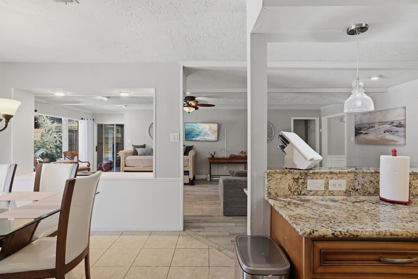 A spacious kitchen with granite countertops, a dining area with chairs, and a view to the outside.