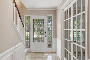A hallway with a white door, a staircase, and a glass door on the right. - 5BD North Houston Home | Pool | Table Tennis (Houston)