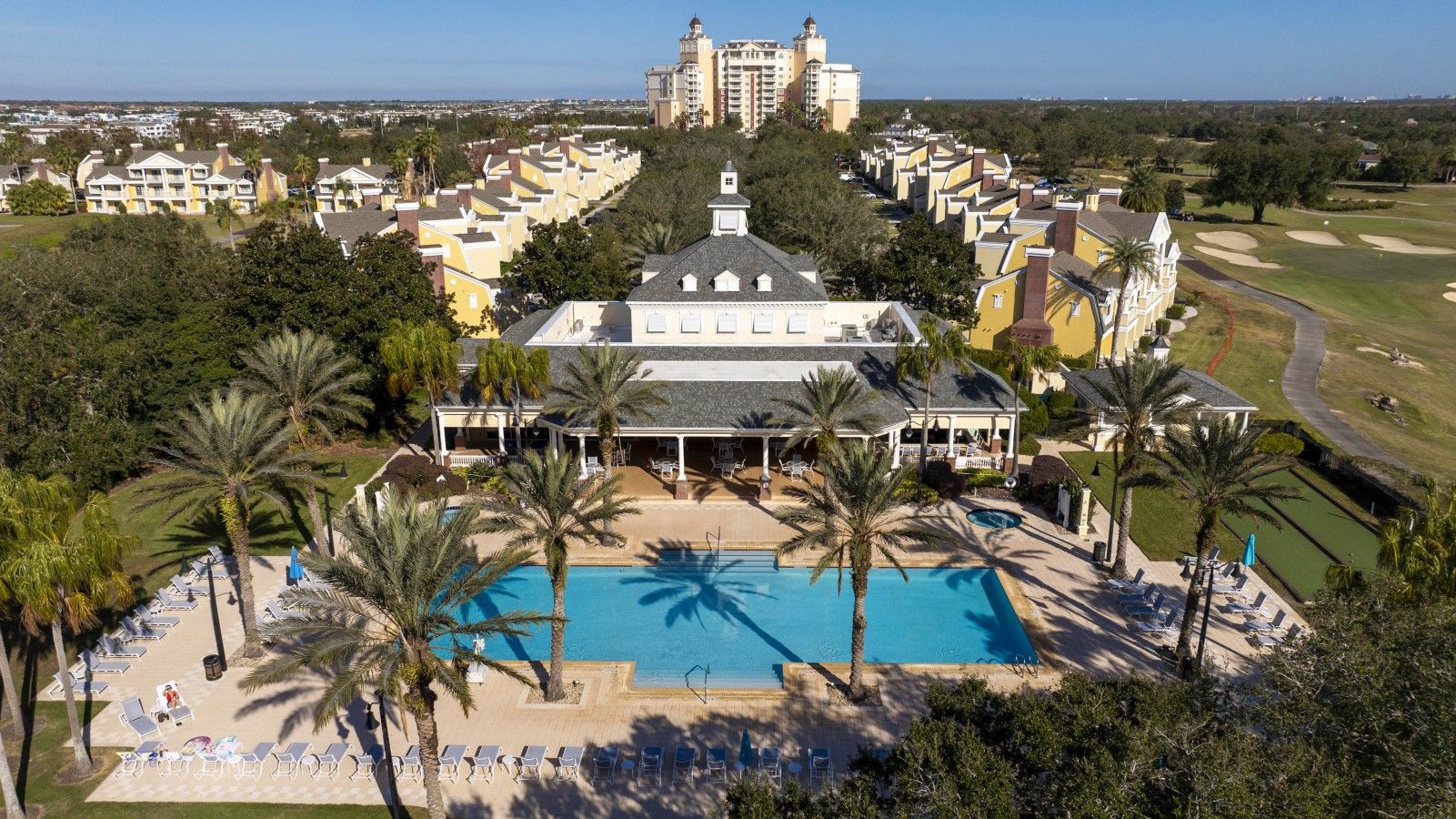 A resort with a central pool, multiple buildings, and a golf course.