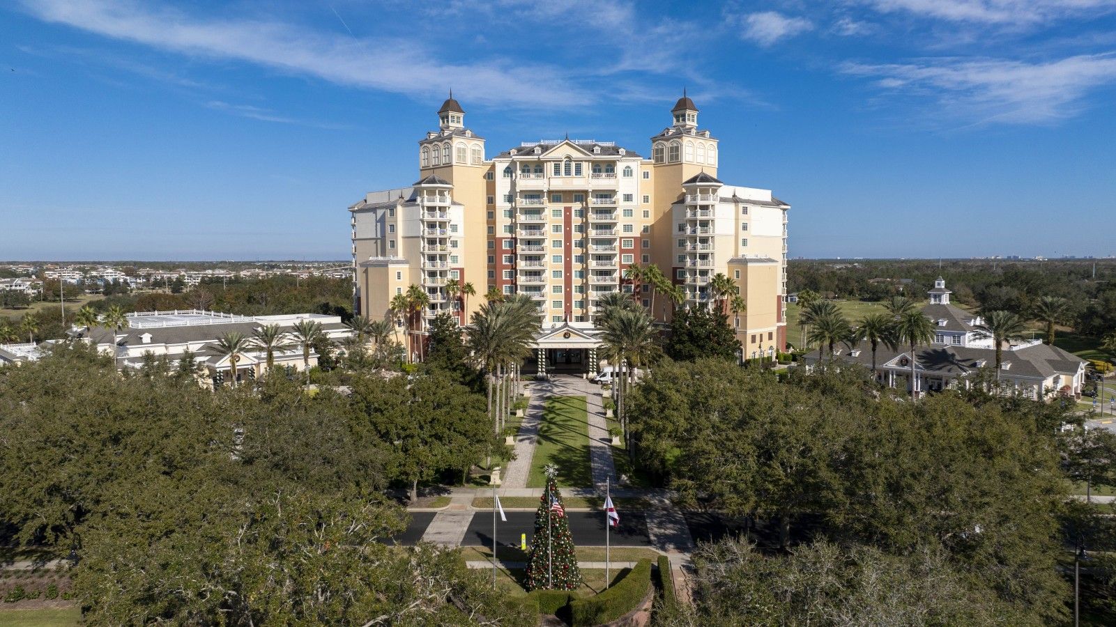 A multi-story hotel with a central courtyard, surrounded by greenery and palm trees.