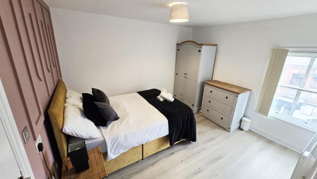 A bedroom with a bed, a wardrobe, a dresser, and a window.