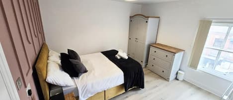 A bedroom with a bed, a wardrobe, a dresser, and a window.