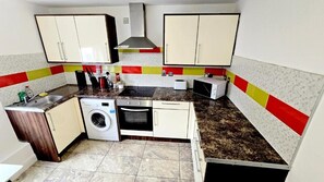 A compact kitchen with a washing machine, microwave, and a small oven. - City centre 2 Bed & 2 Bath Apartment. (Leicester)