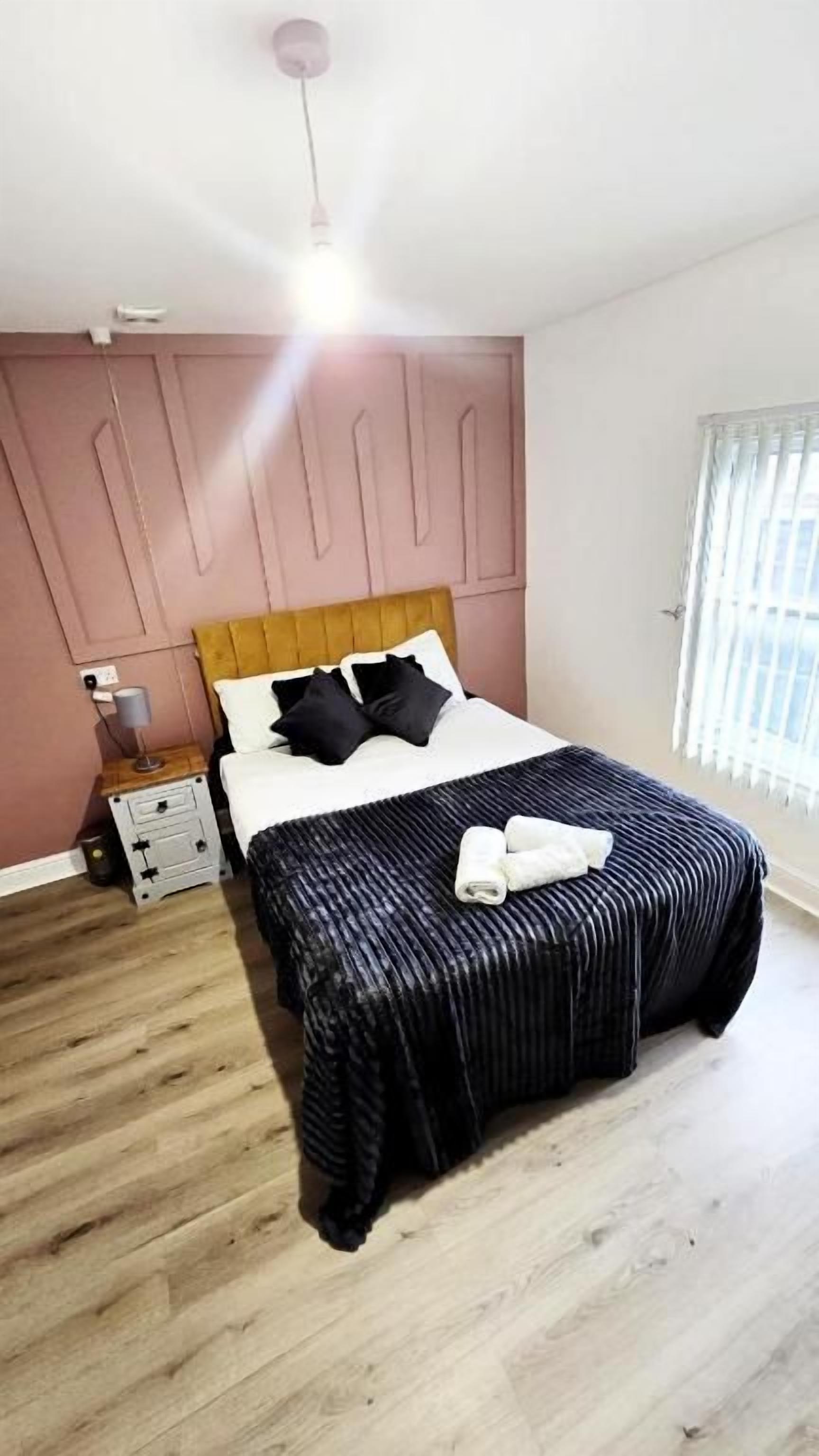 A bedroom with a bed, bedside table, and a window.