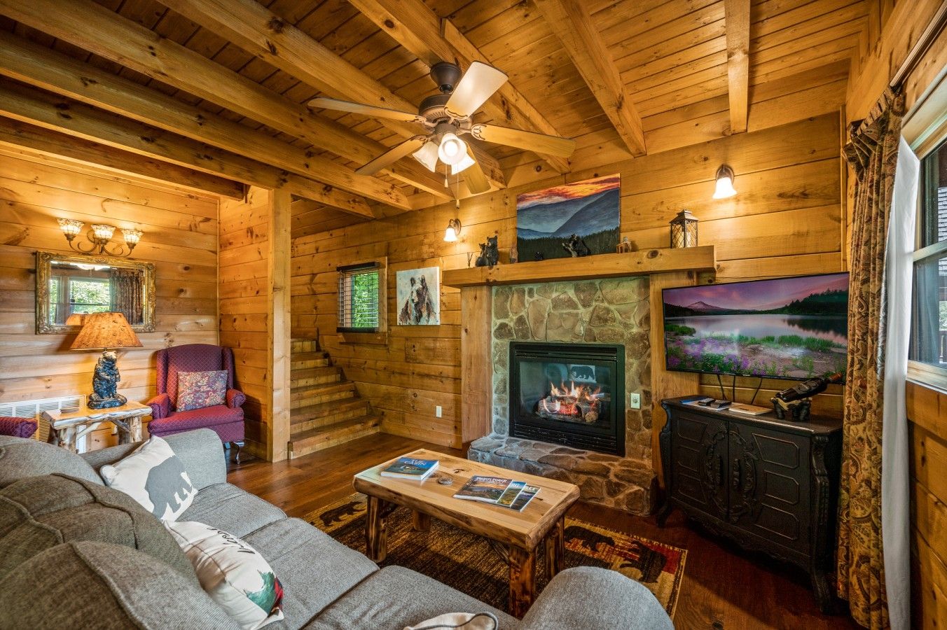 Ein gemütliches Blockhaus-Interieur mit Kamin, Fernseher und einer bequemen Sitzecke.