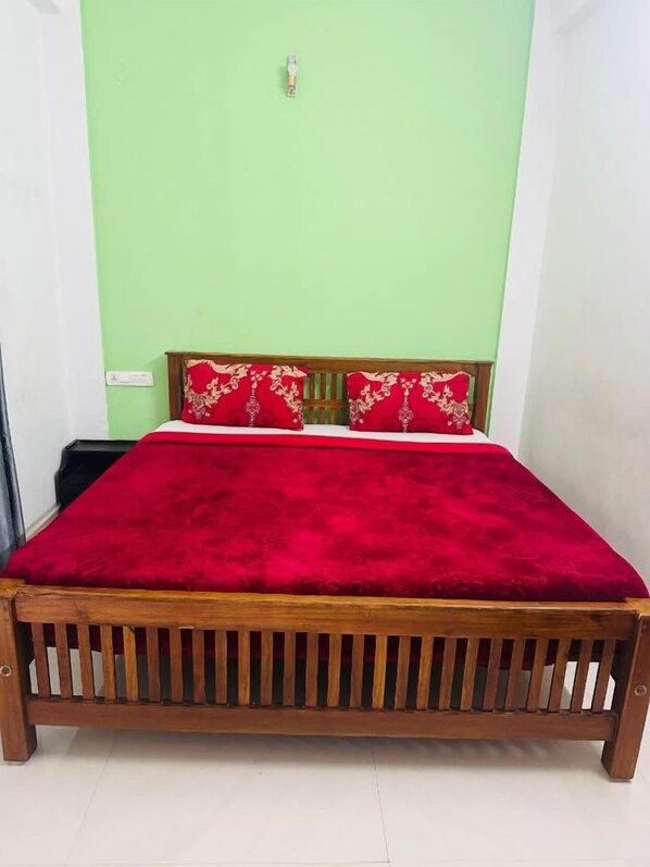 A bed with a red blanket and wooden headboard in a room with green walls. - MSP Amma Cottage (Munnar)
