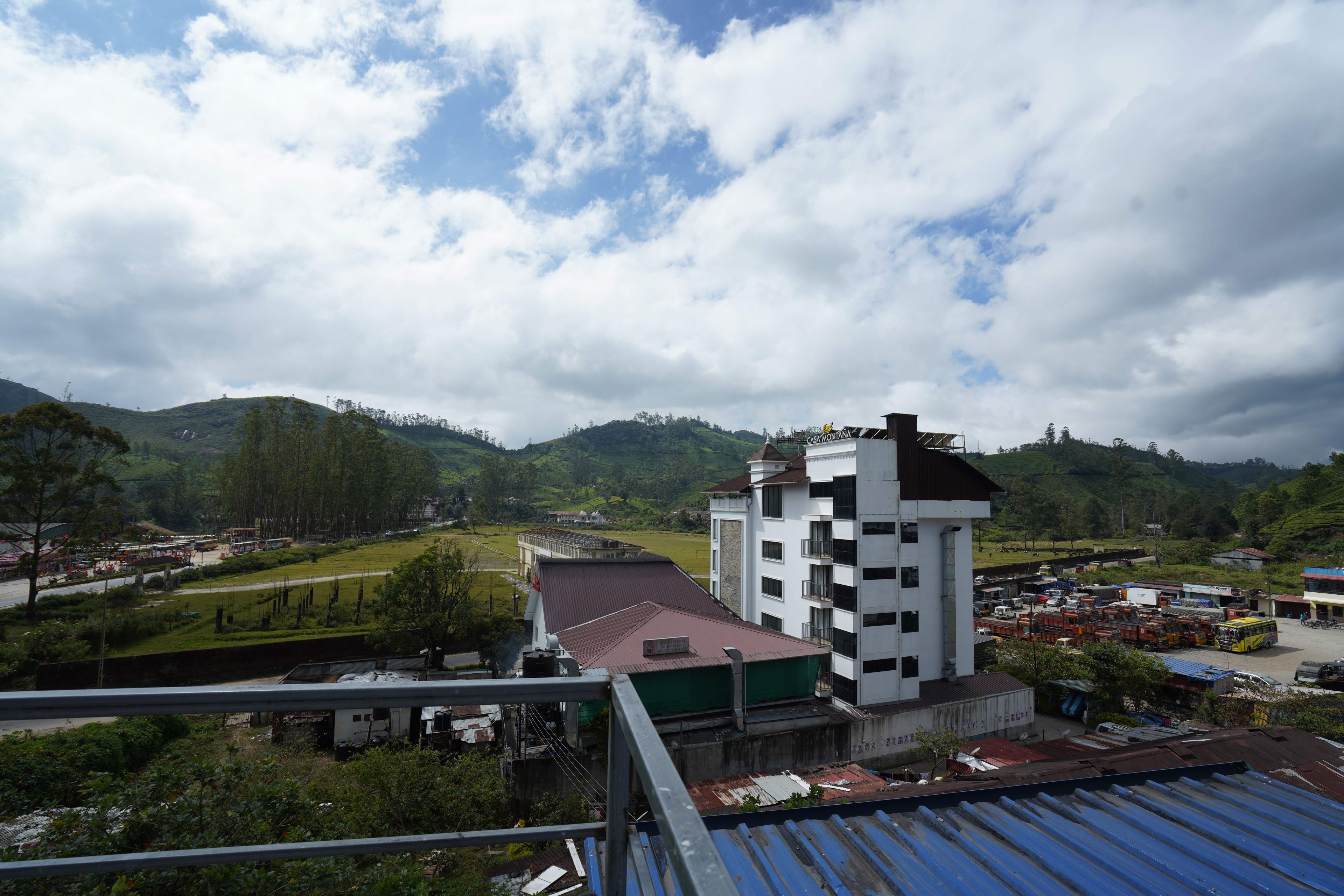 Un immeuble à plusieurs étages, doté d’un toit plat, entouré de verdure et de collines.