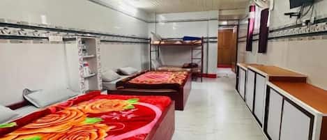 A hotel room with a long corridor, wooden bunk beds, a television, and a tiled floor.