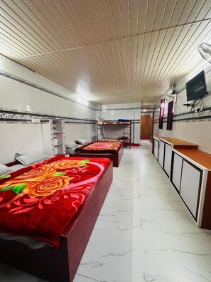A hotel room with a long corridor, wooden bunk beds, a television, and a tiled floor. - MSP Amma Cottage (Munnar)