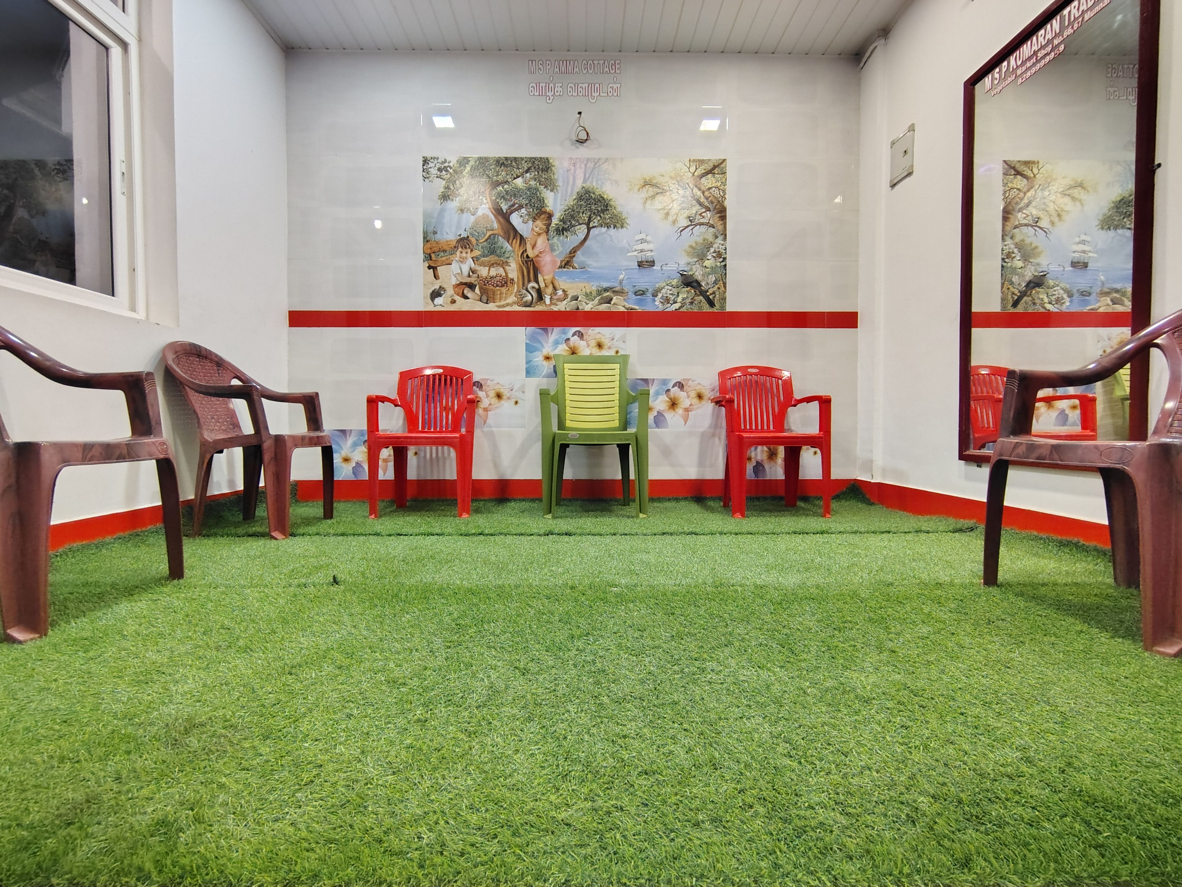 Una habitación con suelo de césped artificial, una mesa con sillas y decoración mural.