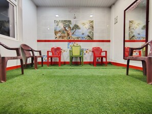 A room with artificial grass flooring, a table with chairs, and decorative wall art.